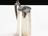 a silver pitcher with a handle on a white table