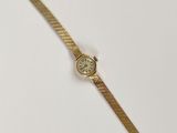 une montre en or sur une surface blanche avec un fond blanc