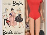 une poupée Barbie dans une boîte, avec plein de vêtements dessus
