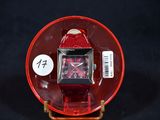 a red watch sitting on a red plate on a black surface