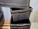 trois bacs en plastique noir empilés sur une palette en bois