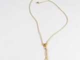 a gold necklace with a black pearl on a white background