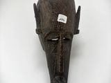un masque en bois accroché au mur, muni d'une étiquette