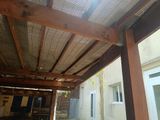 a wooden patio with a metal roof and a table and chairs