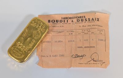 un lingot d'or et un reçu posés sur une table blanche, sur fond blanc