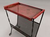 une table en métal rouge sur laquelle est posé un panier