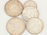 six types différents de pièces d'argent sur une surface blanche