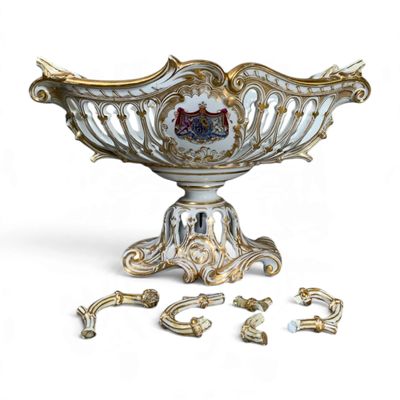 un bol blanc et doré posé sur un socle, à côté d'autres bijoux
