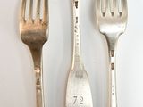 three forks and two spoons on a white table