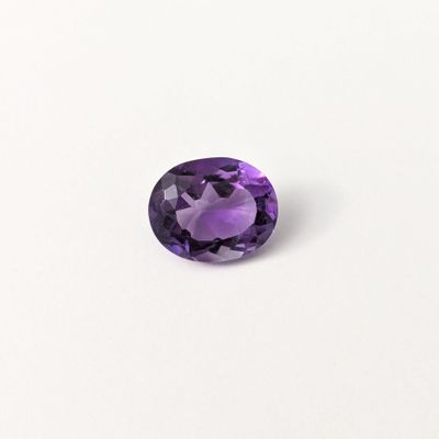 gros plan d'une pierre précieuse violette sur une surface blanche