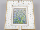 un cendrier blanc et doré orné d'une peinture représentant un arbre