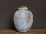 un vase bleu posé sur une table en bois, sur fond noir