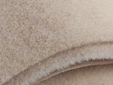 close up of a pile of beige wool material on a white surface