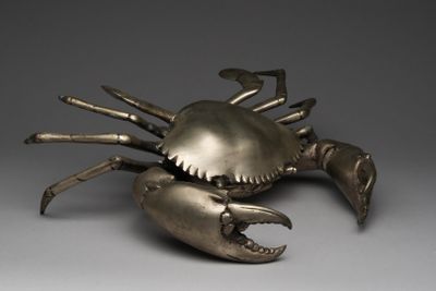 an image of a metal sculpture of a crab on a gray surface