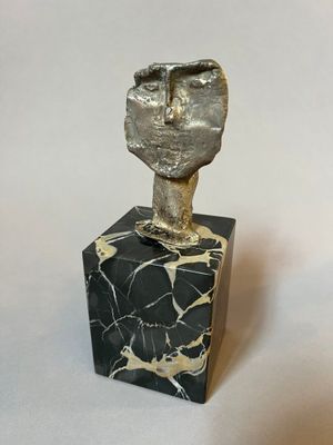 sculpture of a fist on a marble block on a white background