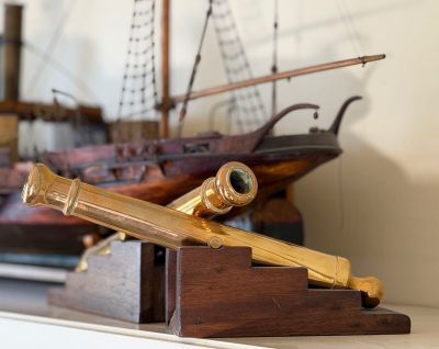 a small model of a ship and a telescope on a shelf