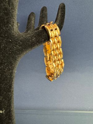 un bracelet en or suspendu à un arbre, avec un ciel bleu en arrière-plan