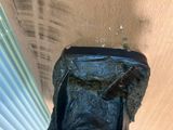 someone is holding a cell phone in a plastic bag on a window sill