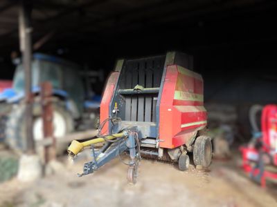 a tractor and a trailer in a barn with other farm equipment