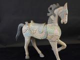 une petite statue représentant un cheval, posée sur une surface noire