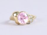 a close up of a pink sapphire and diamond ring on a white surface