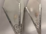 pair of silver plated triangular shaped mirrors on a white surface