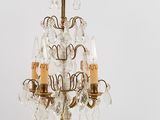 brass and crystal chandelier with three candles on a white background