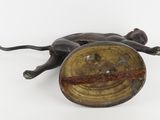 bronze figurine of a cat laying on its back on a white surface