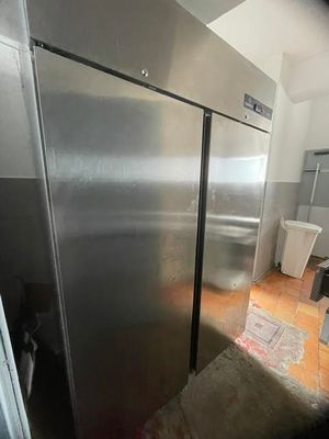 a stainless steel refrigerator in a kitchen next to a trash can