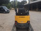the back end of a small yellow tractor parked in a parking lot