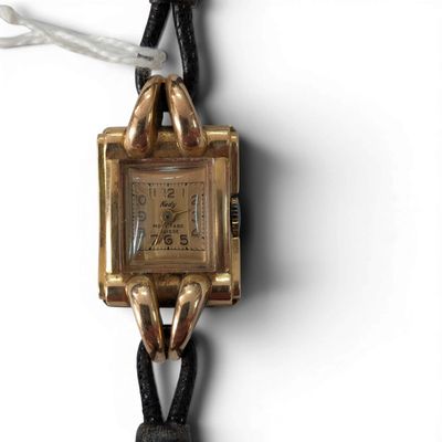 a gold wrist watch with a black leather strap