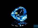 a close up of a blue diamond on a black surface