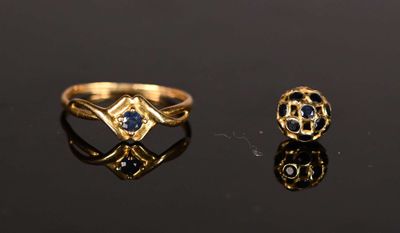 two gold rings with sapphires and diamonds on a black surface