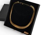 a black box with a gold necklace in it on a white surface