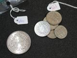 a pile of silver coins and a silver coin with a price tag