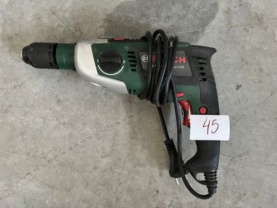 une perceuse filaire posée par terre, avec une étiquette de prix accrochée dessus