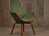 une chaise verte aux pieds en bois dans une pièce