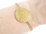 a gold bracelet with a coin on it on a woman ' s arm