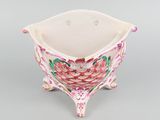 underside view of a pink and white flowered planter on a gray surface