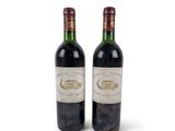 two bottles of wine sitting next to each other on a white surface