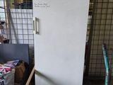 a white refrigerator in a room with a lot of stuff on the floor