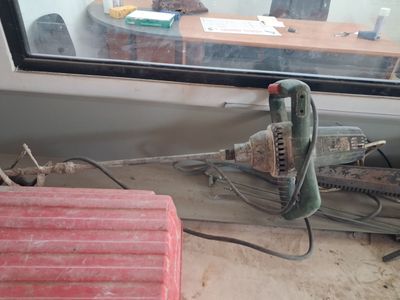 une photo d'une perceuse filaire posée par terre devant une fenêtre