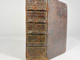 an old book sitting on top of a white table next to a white wall