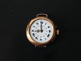 a small gold watch with roman numerals on the face