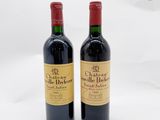 deux bouteilles de vin rouge posées l'une à côté de l'autre sur une surface blanche