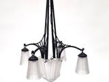 un lustre noir auquel sont suspendus trois abat-jours en verre