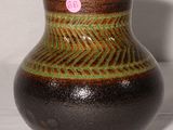 un vase marron et vert posé sur une surface blanche