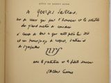 un livre ouvert sur lequel est inscrit un poème manuscrit, posé sur une table