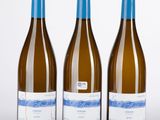 trois bouteilles de vin sont alignées sur une surface blanche