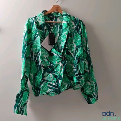 une veste verte suspendue à un cintre accroché au mur